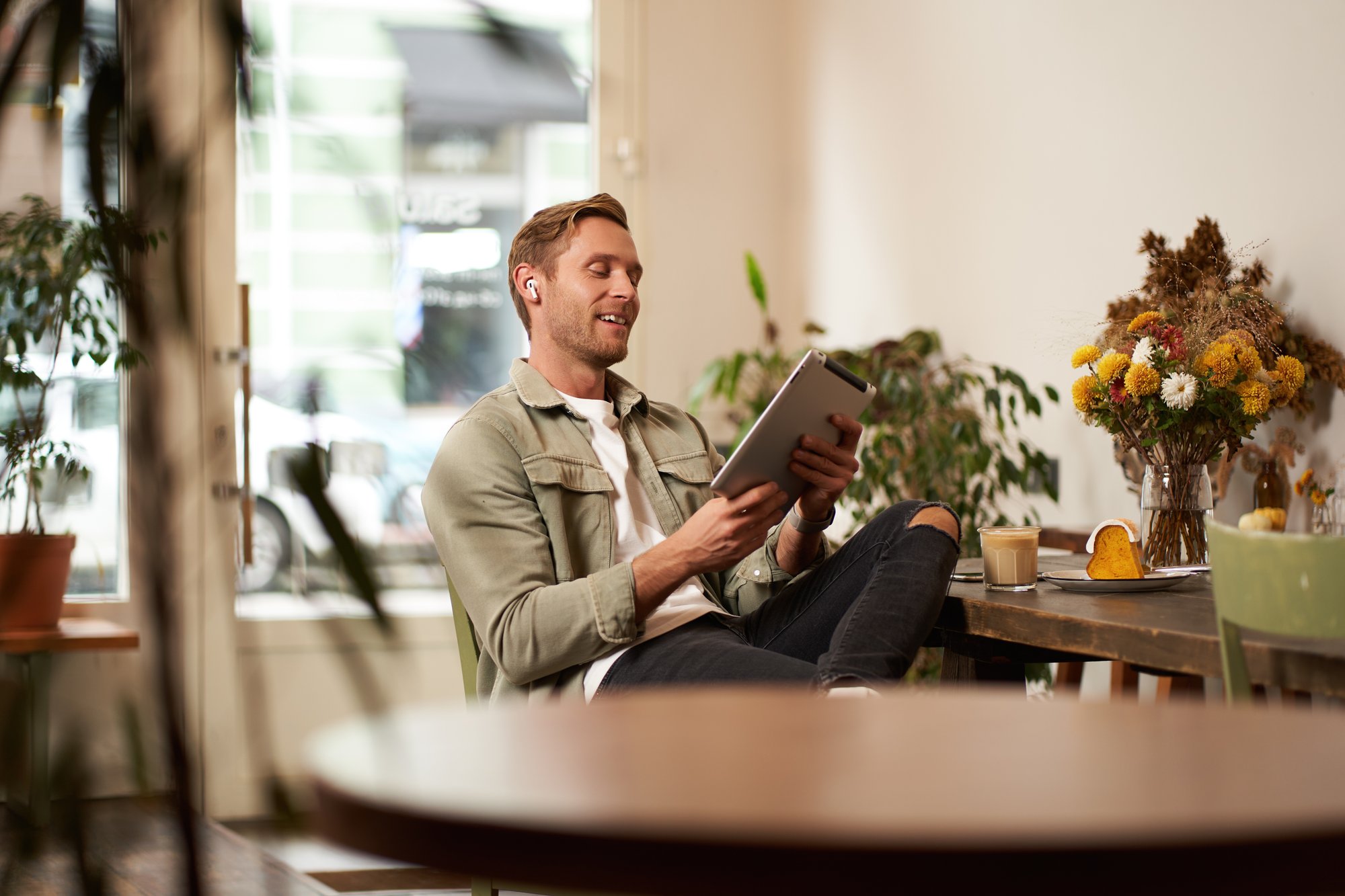 portrait-handsome-smiling-young-man-sitting-coffee-shop-using-digital-tablet-video-chats-with