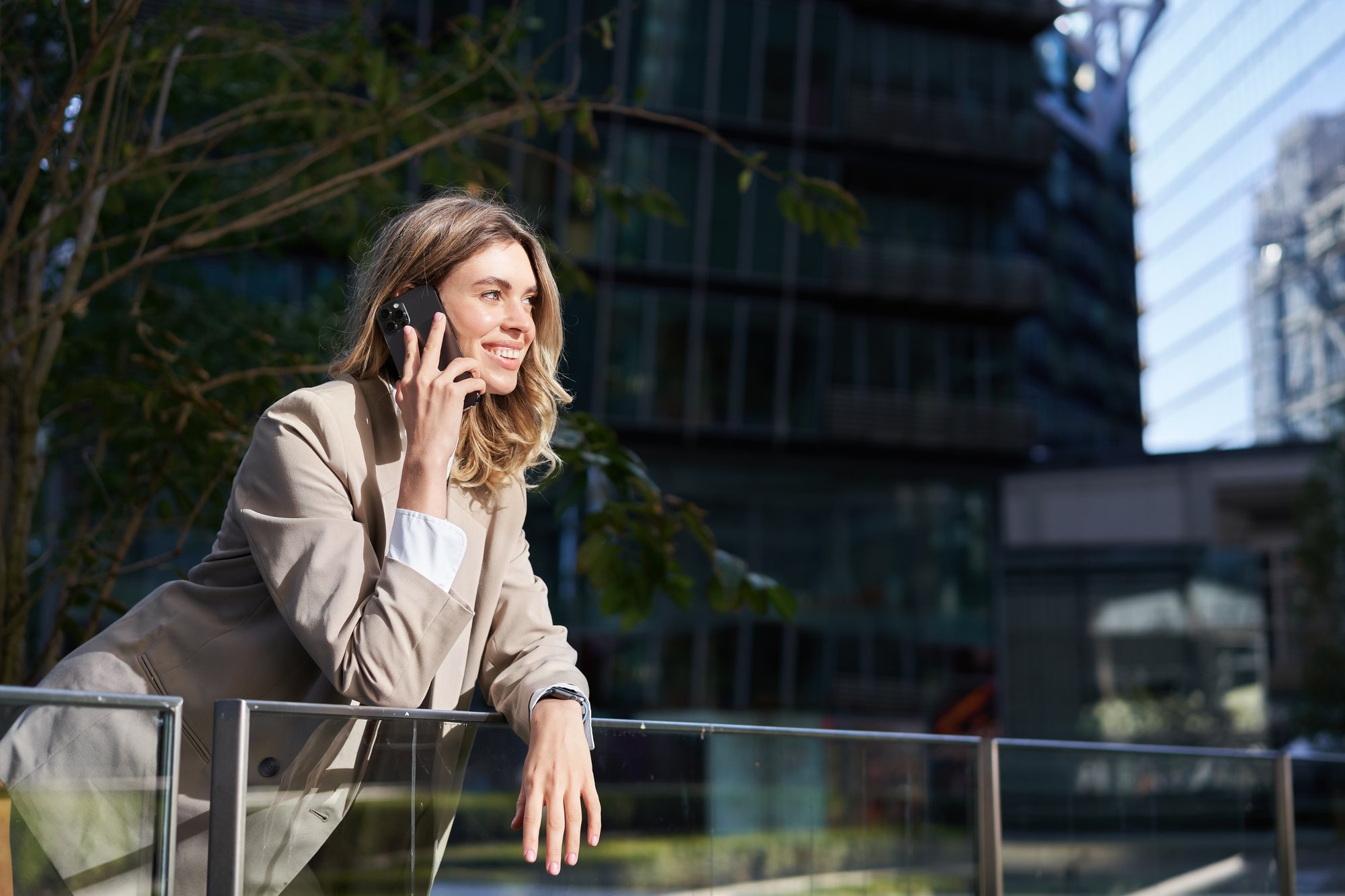 vertical-shot-businesswoman-call-standing-outside-business-center-talking-mobile-phone